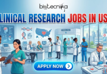 Clinical Research Jobs at Medtronic | Latest Life Sciences Jobs in USA Clinical Research Jobs at Medtronic Latest Life Sciences Jobs in USA. A professional featured image for an article titled "CLINICAL RESEARCH JOBS IN USA," displayed in large, bold blue and red text. The Biotecnika Global logo is centered at the top. The illustration features a bustling clinical research facility with diverse doctors and researchers in lab coats and scrubs, working with medical equipment, patient data, and a map of the USA with a heart icon. The background shows a modern medical center and city skyline. At the bottom center, a prominent blue "APPLY NOW" button is visible. The overall style is modern and informative.