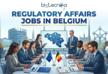 Global Regulatory Affairs Jobs in Belgium | Capgemini Hiring Life Sciences Grads Regulatory Affairs Jobs in Belgium | Capgemini Hiring Now. A professional featured image with the title "REGULATORY AFFAIRS JOBS IN BELGIUM" in prominent blue and gold text, positioned below the Biotecnika Global logo. The illustration depicts a diverse group of corporate professionals in business attire holding a meeting in a modern conference room. On the table are small flags of Belgium and the European Union, alongside documents and laptops. Through large panoramic windows behind them, iconic Brussels landmarks, including the Atomium structure and the European Parliament building, are clearly visible under a bright sky. A screen in the background displays a map of Belgium with regulatory icons.