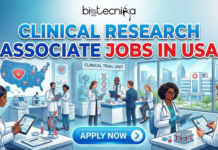 Latest Clinical Research Associate Jobs in USA | Eli Lilly Hiring Now Latest Clinical Research Associate Jobs in USA Eli Lilly Hiring Now. A professional featured image titled "CLINICAL RESEARCH ASSOCIATE JOBS IN USA" in large blue and red text, with the Biotecnika Global logo centered at the top. The illustration depicts a dynamic clinical trial unit bustling with diverse professionals in lab coats and business attire working with tablets, medical equipment, and data screens. Background elements include a map of the USA marked with a heart icon and research hubs, DNA models, and a large window overlooking a modern medical center. A prominent glowing blue "APPLY NOW" button is located at the bottom center.