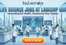 Hiring Now! Life Science Jobs in the USA | You Can’t Afford to Miss at Labcorp Life Science Jobs in USA New Job Vacancy at Labcorp. A professional recruitment banner for Biotecnika Global titled "LIFE SCIENCE JOBS AT LABCORP USA" with the subtitle "Innovating for Health, Advancing Your Career." The illustration shows a diverse team of scientists in a modern, spacious laboratory working with advanced automated equipment, microscopes, and large digital screens displaying DNA structures. Large windows in the background overlook a city skyline and a research park. A glowing orange "APPLY NOW" button is centrally located at the bottom.