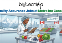Quality Assurance Jobs at Metro Inc | Regulatory Role in Ontario Canada Quality Assurance Jobs at Metro Inc Canada. An illustration titled "Quality Assurance Jobs at Metro Inc Canada" by Biotecnika Global. The image depicts a female quality assurance specialist wearing a lab coat and hairnet, holding a tablet and clipboard while inspecting fresh produce like berries, apples, and lettuce on a metal table. She is working inside a bright Metro grocery store, marked by a "metro" sign and hanging Canadian flags, with a view of snowy mountains and a city skyline through large windows in the background.