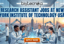 Research Assistant Jobs at New York Institute of Technology USA | Biology Apply Now A vibrant featured image for a job announcement. At the top is the 'biotecnika Global' logo. Below it, large bold text reads: 'RESEARCH ASSISTANT JOBS AT NEW YORK INSTITUTE OF TECHNOLOGY USA'. The illustration depicts a diverse team of scientists in a modern, high-tech laboratory working with holographic displays, robotic arms, and microscopes, set against a panoramic sunset view of the New York City skyline. A glowing orange 'APPLY NOW' button is located at the bottom center.