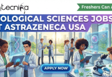 High-Paying Biological Sciences Jobs at AstraZeneca USA | Freshers Can Apply! Biological Sciences Jobs at AstraZeneca USA Freshers Can Apply. A featured image for a job advertisement titled "BIOLOGICAL SCIENCES JOBS AT ASTRAZENECA USA." The graphic features a diverse team of young scientists in white lab coats collaborating in a bright, high-tech laboratory. They are using modern tools like tablets and microscopes, with glowing holographic displays of DNA helices and cellular structures floating in the air. Large windows in the background reveal a sunlit, green campus. The Biotecnika Global logo is in the top left, a green ribbon banner in the top right reads "Freshers Can Apply," and a glowing blue "Apply Now" button is at the bottom center.