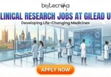 Clinical Research Jobs in UK | Apply For Clinical Trials Job at Gilead Clinical Research Jobs in UK Apply For Clinical Trials job at Gilead. A sleek recruitment banner for Biotecnika Global titled "CLINICAL RESEARCH JOBS AT GILEAD UK" with the subtitle "Developing Life-Changing Medicines." The illustration features a diverse team of scientists in a high-tech biopharmaceutical laboratory. They are interacting with large holographic touchscreens displaying molecular structures and clinical data. Through the expansive glass windows, the London skyline is visible, including Big Ben, the Palace of Westminster, and the Shard. A bright orange "APPLY NOW" button is centered at the bottom.