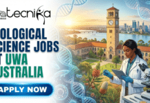 Biological Science Jobs in Australia | Apply For Research Associate at UWA Biological Science Jobs at UWA Australia | Don't Miss It. A featured image for a job advertisement titled "Biological Science Jobs at UWA Australia." The illustration features a female scientist in a white lab coat conducting research in an outdoor laboratory setting. In the background, the iconic Winthrop Hall clock tower of the University of Western Australia is visible alongside the Swan River and the Perth skyline at sunset. The scene is decorated with glowing DNA helices, microscopic cells, and native Australian flora like Banksia flowers. The Biotecnika Global logo is at the top left, and a bright blue "Apply Now" button is at the bottom left.