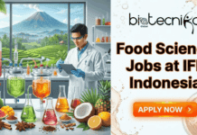 Latest Food Science Jobs at IFF Indonesia You Can’t Ignore Food Science Jobs at IFF Indonesia You Can’t Ignore. A promotional banner for "Food Science Jobs at IFF Indonesia" from Biotecnika Global. The left side features a male food scientist in a lab coat working with various beverage experiments, fresh fruits, and spices, with a tropical Indonesian landscape and volcano in the background. The right side has large orange text reading "Food Science Jobs at IFF Indonesia" above a glowing orange "APPLY NOW" button.