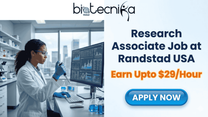 Research Associate Job at Randstad USA Earn Upto $29Hour. A job advertisement banner from Biotecnika Global. The top left shows the Biotecnika Global logo. The left half of the image features a Black woman in a lab coat, safety glasses, and gloves working with scientific equipment and a large computer monitor displaying data in a modern laboratory with a city skyline view. The right half of the image has large text that reads: 'Research Associate Job at Randstad USA' and 'Earn Upto $29/Hour'. Below the text is a blue button with the text 'APPLY NOW'.