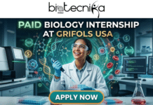 Exciting Paid Biology Internship in USA | Grifols Hiring For R&D Intern Role Exciting Paid Biology Internship in USA Grifols Hiring For R&D Intern Role. A dynamic recruitment image for Biotecnika Global advertising a "PAID BIOLOGY INTERNSHIP AT GRIFOLS USA". The Biotecnika Global logo is at the top. Large headline text in green and gold reads "PAID BIOLOGY INTERNSHIP" above the white text "AT GRIFOLS USA". The central figure is a smiling young woman in a white lab coat, safety glasses, and nitrile gloves, holding a multi-channel pipette over a multi-well plate. She is surrounded by complex, glowing holographic visualizations of DNA helices, molecular structures, and human cells (erythrocytes and lymphocytes). Small "PAID" labels and dollar signs ($) float within the data visualization. The background shows a modern lab with robotic equipment, computer screens with data, beakers, and test tube racks. At the very bottom center, a prominent button with a teal-to-orange gradient says "APPLY NOW".