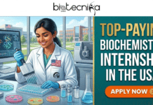 Top-Paying Biochemistry Internship in the USA | Earn upto $27/hr Top-Paying Biochemistry Internship in the USA | Earn upto $27/hr. An illustrated featured image banner split between a laboratory scene and a text panel. Across the top is a white header with the black logo "biotecnika Global". The left side features a smiling female biochemist of South Asian descent wearing a white lab coat with an American flag patch and gloves. She operates a multi-channel pipette over a 96-well plate on a benchtop surrounded by petri dishes with colorful cultures, glassware containing blue and pink liquids, laboratory equipment, and a computer monitor displaying 3D molecular structures. A large window behind her shows a university campus setting under a clear sky. The right side is a dark teal patterned panel with large, bold stacked text reading, "TOP-PAYING BIOCHEMISTRY INTERNSHIP IN THE USA" in white and gold lettering. Below the text is a prominent orange button that reads, "APPLY NOW" with a right-pointing arrow icon.