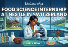 Food Science & Biology Students: Nestlé Hiring Food Science Interns in Switzerland – Apply Now! Food Science & Biology Students Nestlé Hiring Food Science Interns in Switzerland – Apply Now! A promotional featured image for a job page advertising a Food Science Internship at Nestlé in Switzerland, with the biotecnika Global logo at the top. The image depicts a diverse woman researcher in a lab coat sitting at a modern lab bench, intensely looking through a microscope. The bench is set with test tubes, cocoa pods, milk, and a molecule model. Through a large window behind her, a breathtaking panoramic view of the snow-capped Swiss Alps, a classic Swiss chalet, and an alpine lake is visible, establishing the location. The image is an attractive, scroll-stopping digital illustration. A prominent, glowing "APPLY NOW" button is centered at the bottom.