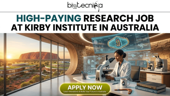 High-Paying Research Job in Australia – Join Kirby Institute as a Research Officer Today! An informative featured image banner for a high-paying research job at the Kirby Institute in Australia. At the top center, the biotechnika Global logo is displayed above large, bold text reading: 'HIGH-PAYING RESEARCH JOB AT KIRBY INSTITUTE IN AUSTRALIA'. The banner shows a female researcher in a lab coat looking into a microscope in a futuristic office with massive, curved windows. Through the windows, a dramatic sunset view of Uluru (Ayers Rock) in the Australian outback is visible, with modern, green-roofed buildings nearby. Multiple computer screens display detailed scientific data and a 3D model of a labeled virus (retrovirus, suitable for Kirby Institute focus) with miniature kangaroo and koala figures. On her desk are more microscopes, textbooks, and a boomerang-shaped pen holder with a koala figure. A prominent yellow 'APPLY NOW' button is at the bottom center, with smaller text below reading: 'Lead Innovations & Build Your Future in Australia.' and 'PREMIUM BRANDS, NO COMPANY'. The entire composition is visually rich and captures the unique theme.