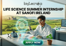 Latest Life Science Summer Internship at Sanofi in Ireland! Get Hands-On Experience Today!! Latest Life Science Summer Internship at Sanofi in Ireland! A detailed promotional banner for the Biotecnika Global 'Life Science Summer Internship at Sanofi Ireland'. The image features a smiling young male scientist in a lab coat and safety glasses using a pipette at a modern lab bench. Centered is a large, detailed green-glowing hologram of a cell with a stylized shamrock nucleus and a DNA helix at its base. The background is a large window with a beautiful view of an Irish castle and rolling green hills. Below the scene, a glowing green button reads 'APPLY NOW'. The text 'biotecnika Global' is at the very top, and the internship title is in large text just below it.