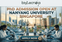 PhD Admission Open in Singapore: NTU Hiring Researchers for Neural Tissue Engineering & Stem Cell Therapy! PhD Admission Open in Singapore NTU Hiring Researchers for Neural Tissue Engineering & Stem Cell Therapy!. A detailed promotional banner for 'PhD Admission Open at Nanyang University Singapore' from biotecnika Global. The image depicts a modern, multi-station laboratory with four scientists in white lab coats and gloves working with microscopes and computer screens displaying molecular data. In the background, seen through massive floor-to-ceiling windows, is a spectacular, sun-drenched panoramic view of a unique modern Nanyang University campus, a generic Singapore cityscape skyline, tropical greenery, and a Merlion statue. Large copper and blue text at the top center reads: 'PhD ADMISSION OPEN AT NANYANG UNIVERSITY SINGAPORE'. At the bottom center, a prominent rounded copper and teal button reads 'APPLY NOW' with an arrow. The entire composition is high-quality, illustrative, and attention-grabbing.
