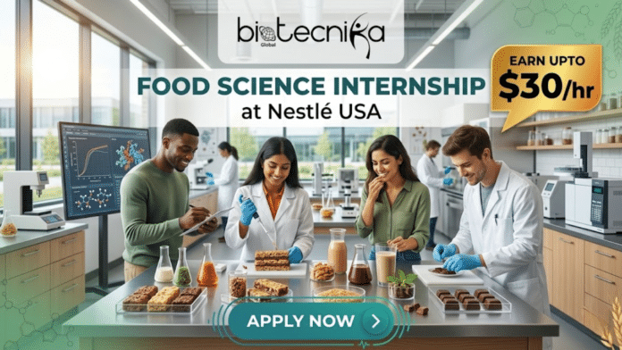 Food Science Internship at Nestlé USA | Launch Your Global Career & Earn Upto $30/hr! An illustrated photograph showing a modern, well-equipped food science research and development laboratory, with a diverse group of four scientists gathered around a central table covered in food samples and scientific equipment. From left to right: a man with short, curly dark hair is taking notes on a clipboard and observing; a woman with short, curly dark hair and glasses uses a pipette to apply a liquid to a multi-layered cake-like structure, smiling; a woman with long, dark hair tastes a drink from a glass with a pleased expression; and a man with short brown hair is adjusting small chocolate candies. The central workspace is filled with beakers containing colorful grains, liquids, and various prepared food items like stacks of gourmet bars, glasses of drinks (such as protein shakes), and rows of chocolates. The high-tech background features large windows looking out onto a modern campus, multiple computer monitors showing graphs, other scientific machinery, and blurred figures of additional lab staff working. A top banner contains the Biotecnika Global logo on the left and text in the center that reads